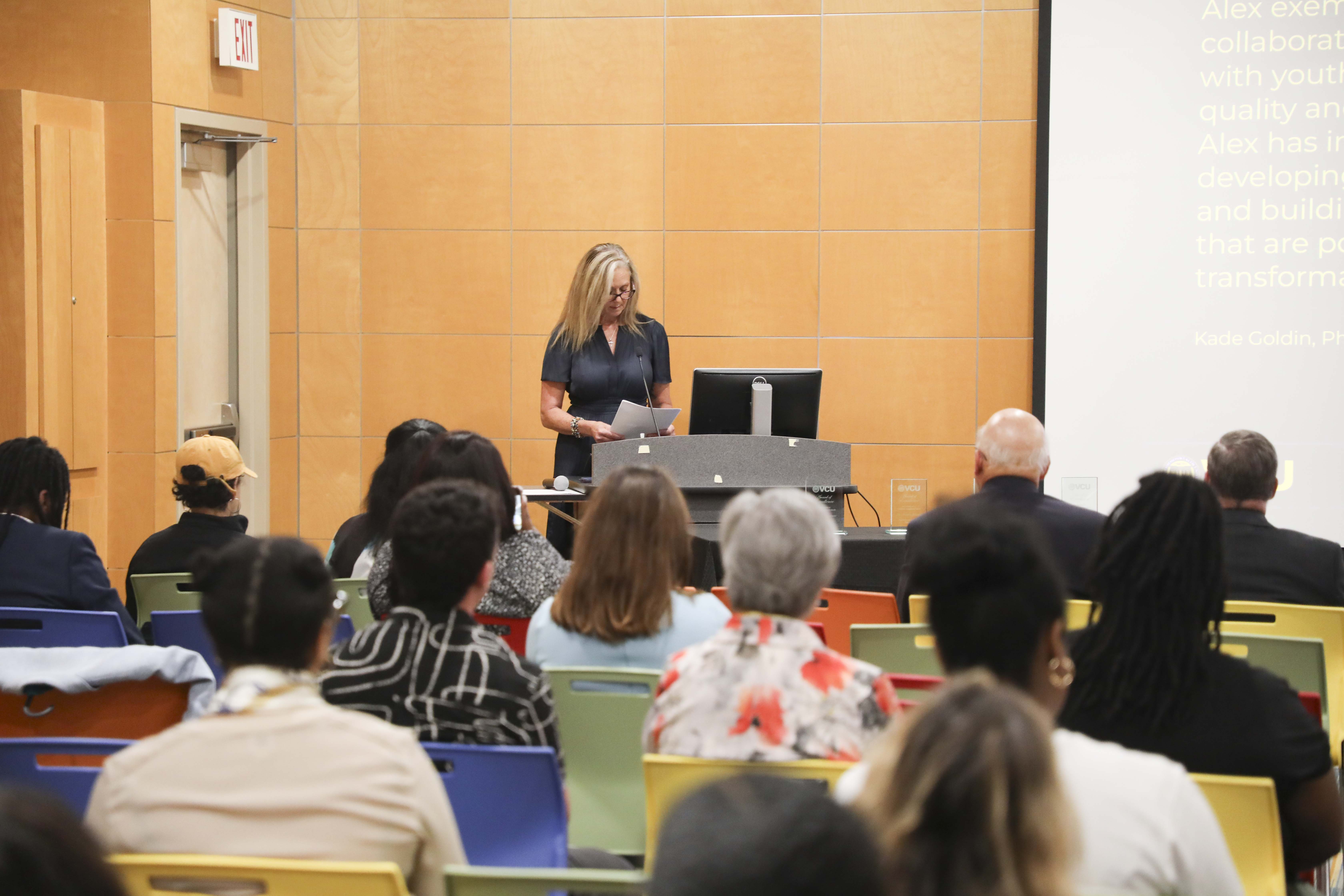 crowd and a woman speaking into microphone