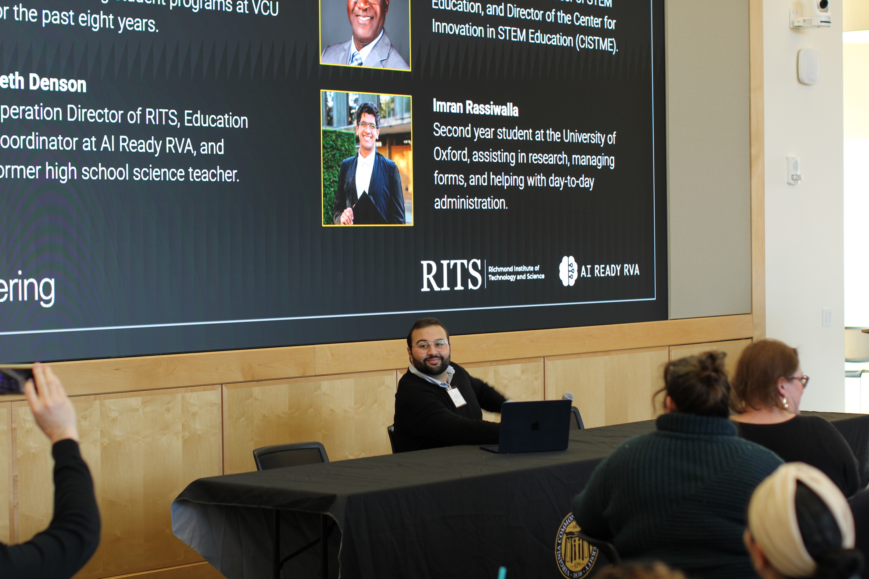 A man speaking in front of a screen