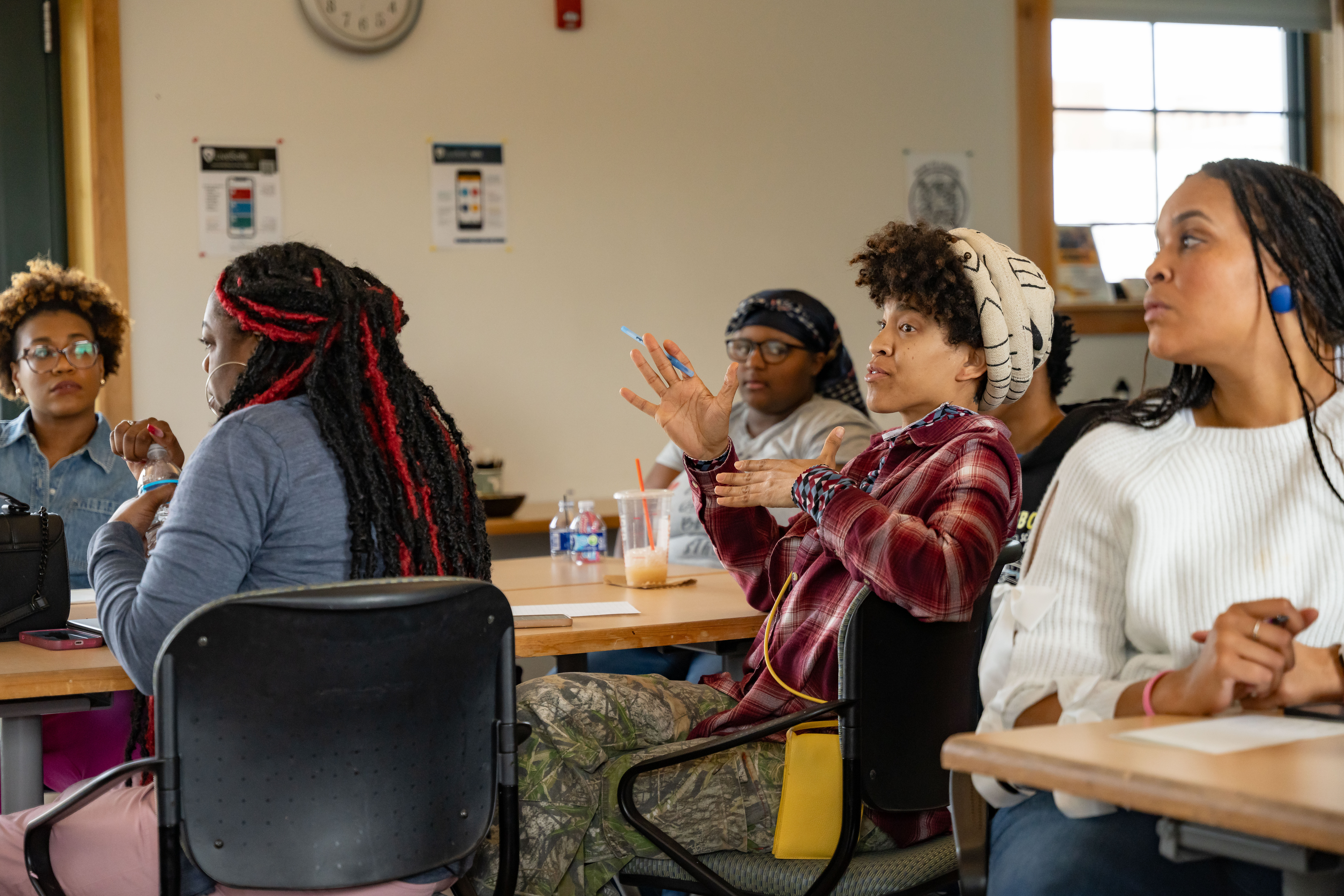student sitting at a table talking with other students