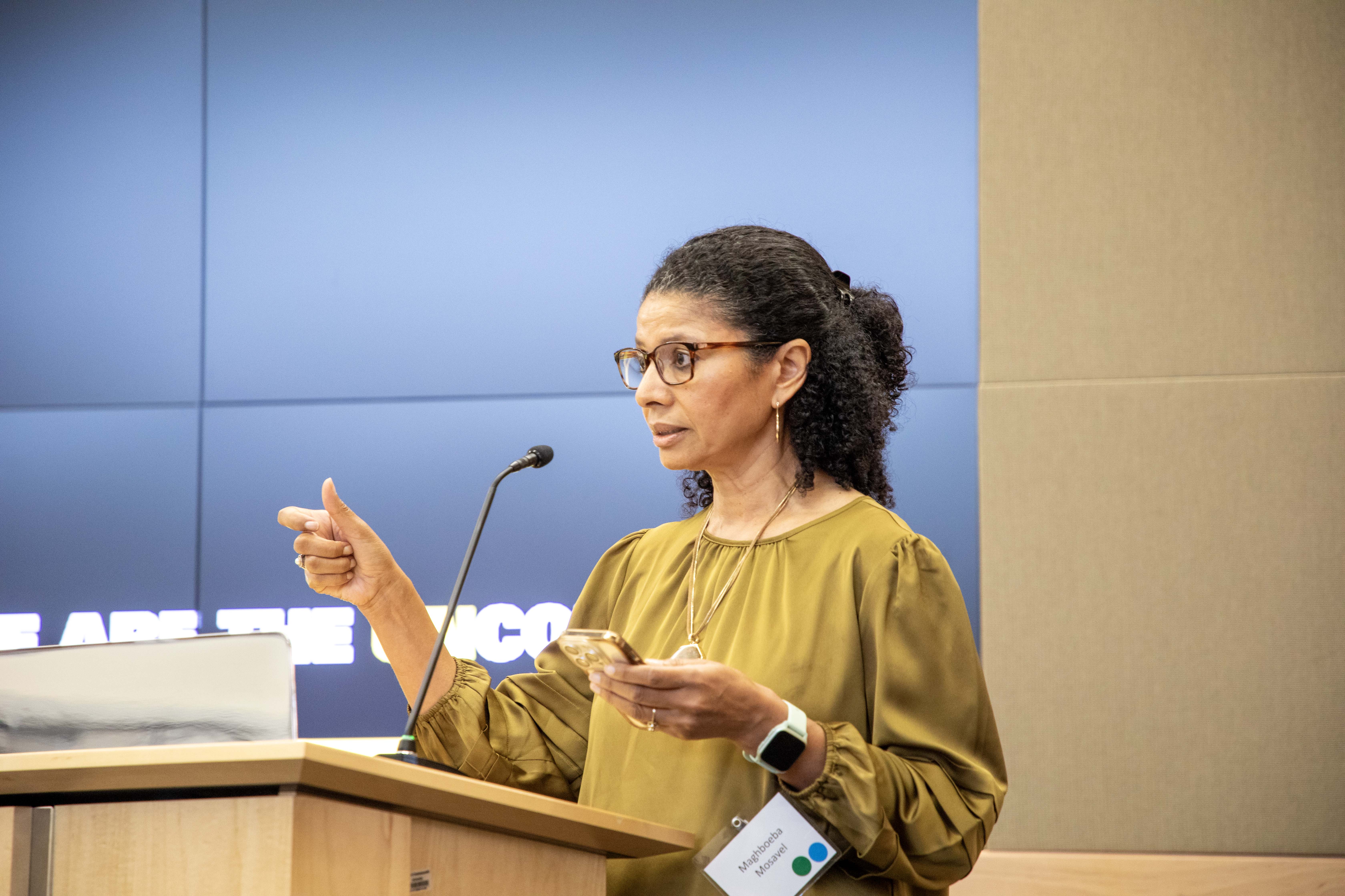 Maghboeba Mosavel talking at a pedestal in a microphone