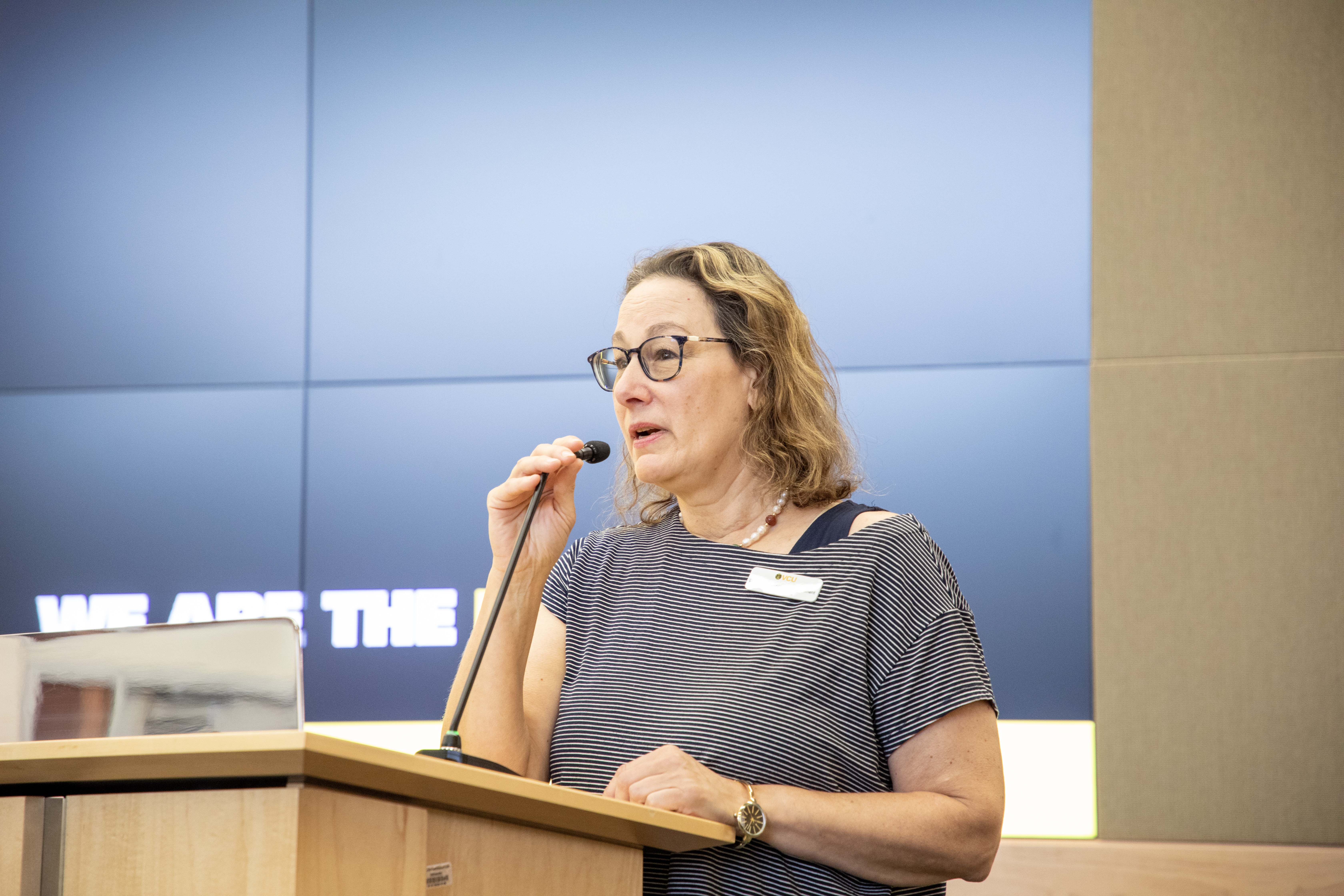 Shari Garmise talking into a microphone at a pedestal