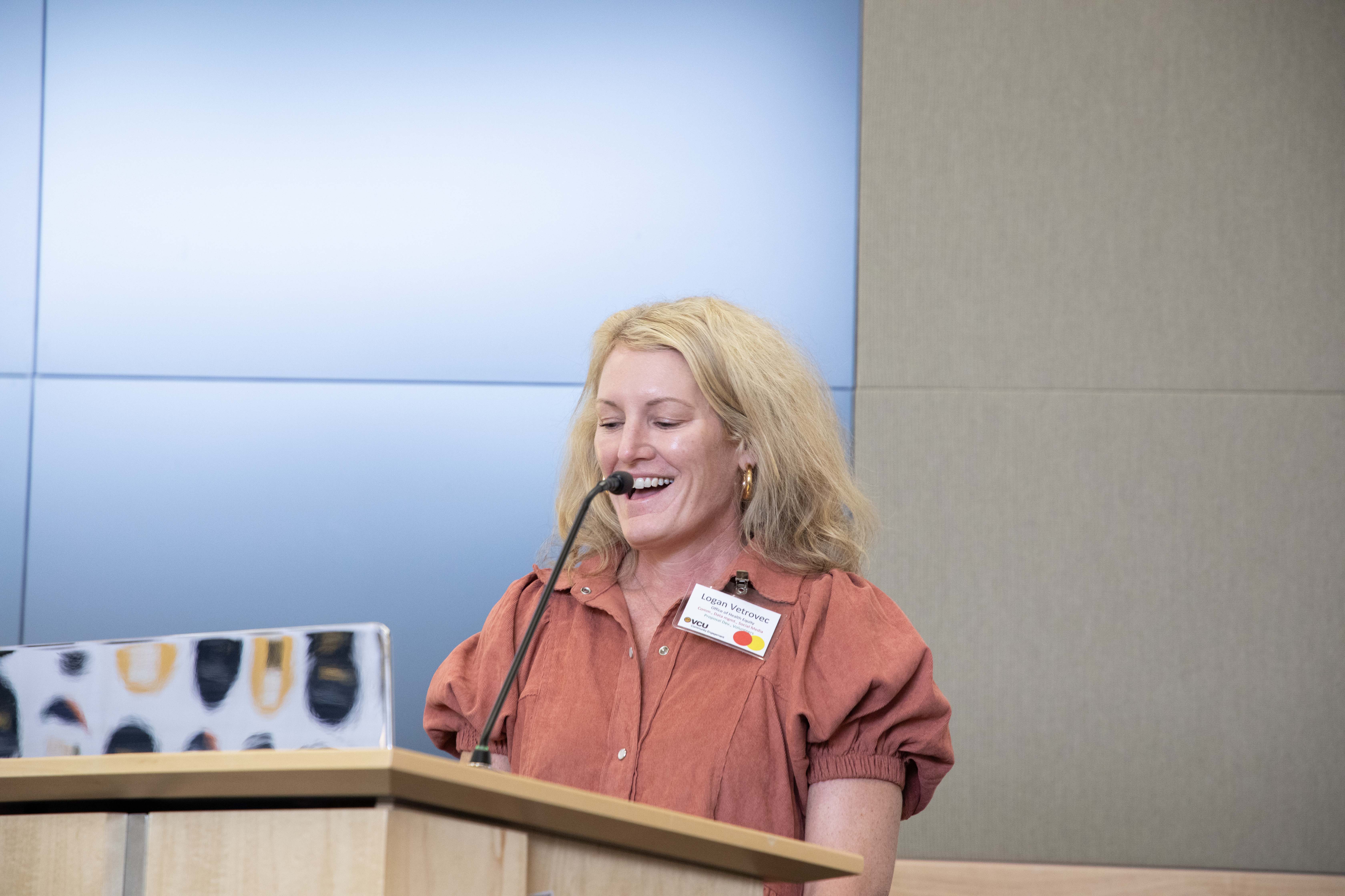 A woman speaking into a microphone at a pedestal