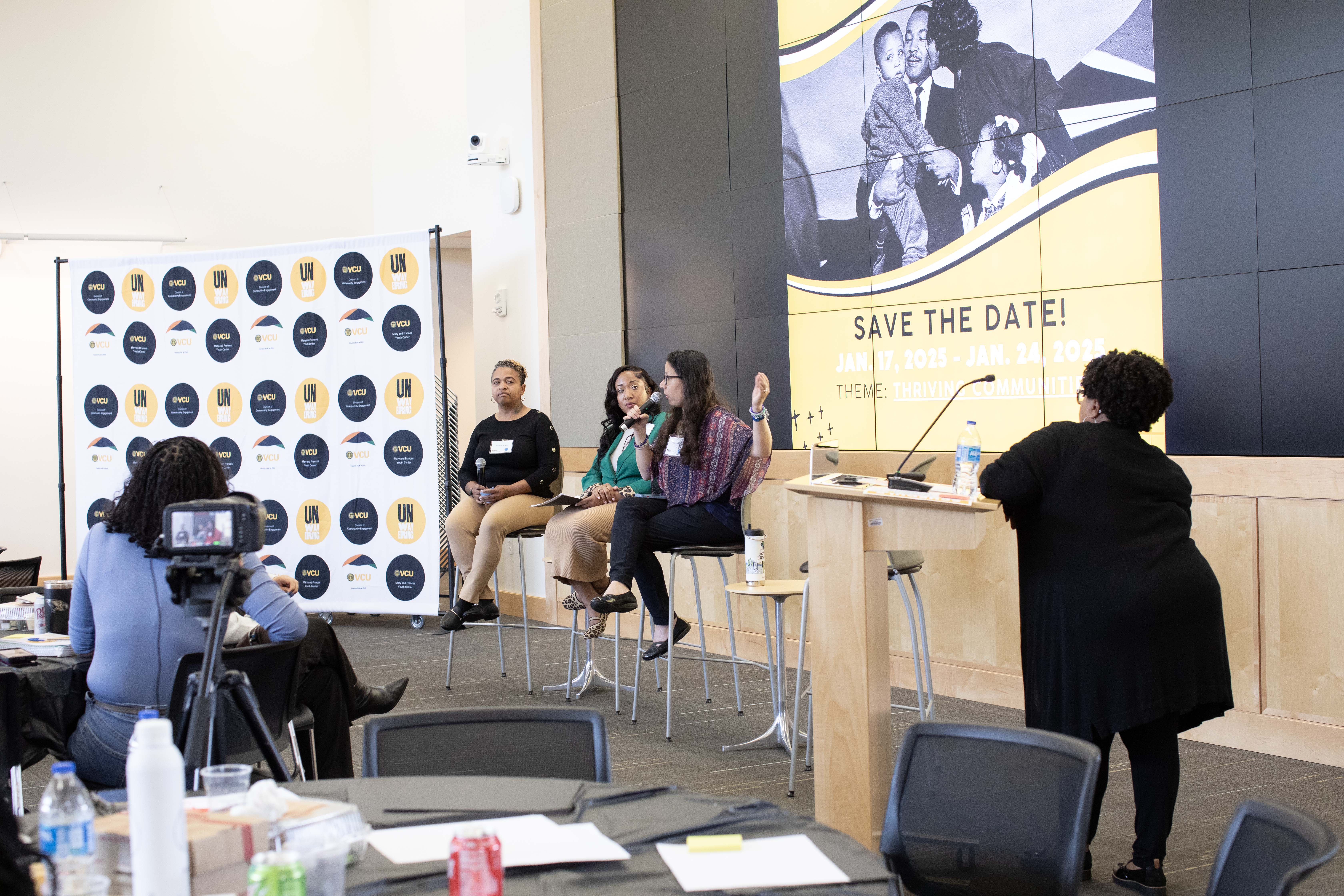 Panel speakers sitting and talking in front of a crowd