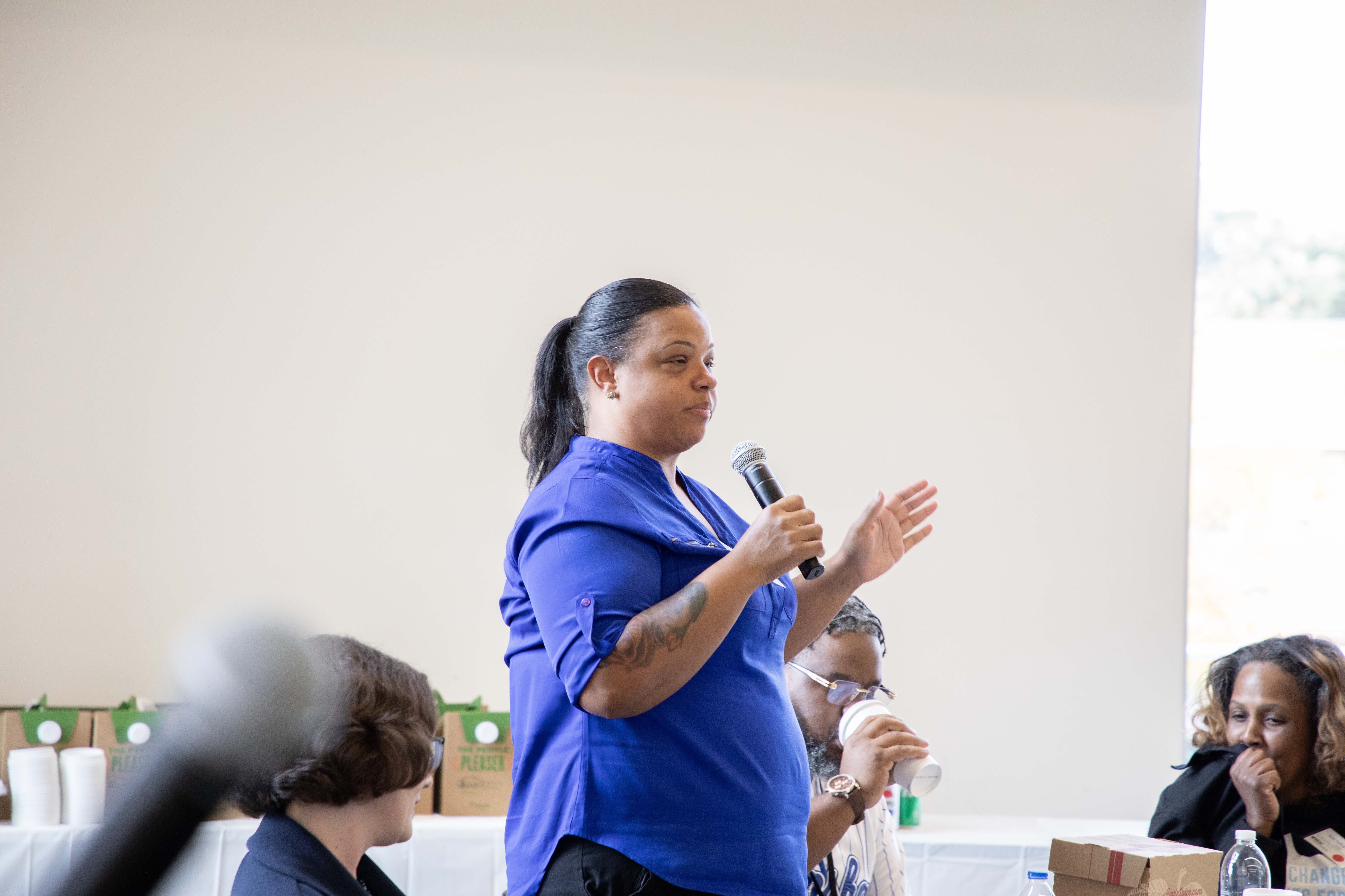 A women standing speaking into a microphone