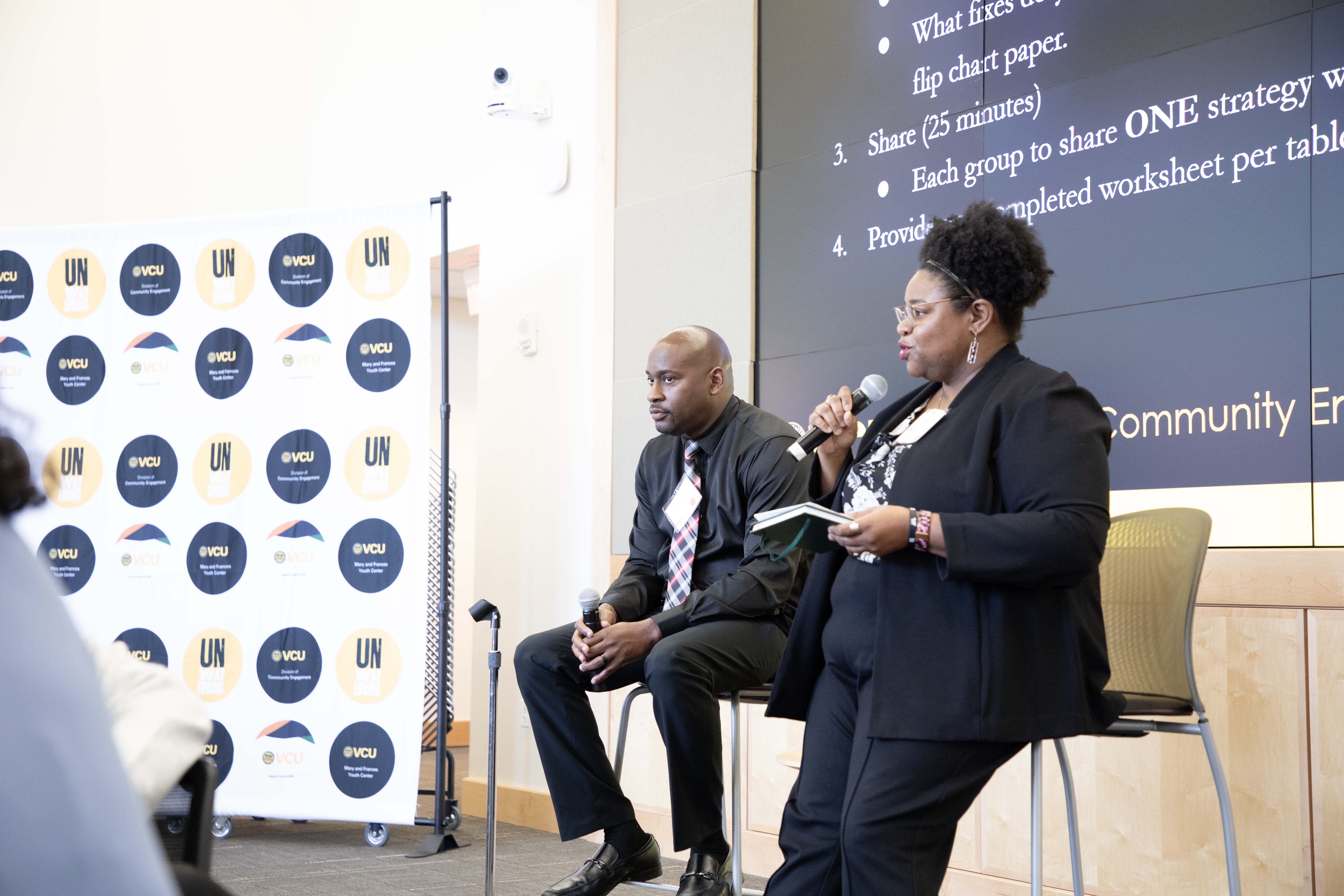 two people sitting in chairs speaking into microphones